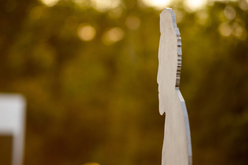 Silhouette of a sculpture titled "Sagoma Anfiteatro" against a blurred green background in Chianti sculpture park.