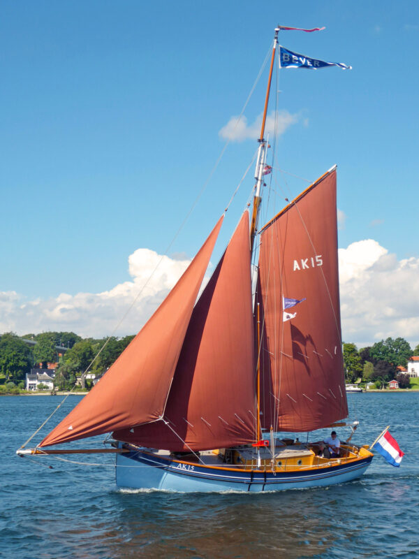 Sailing boat with brown sails and blue hull, named AK15, on water near Svendborg, July 31, 2017.