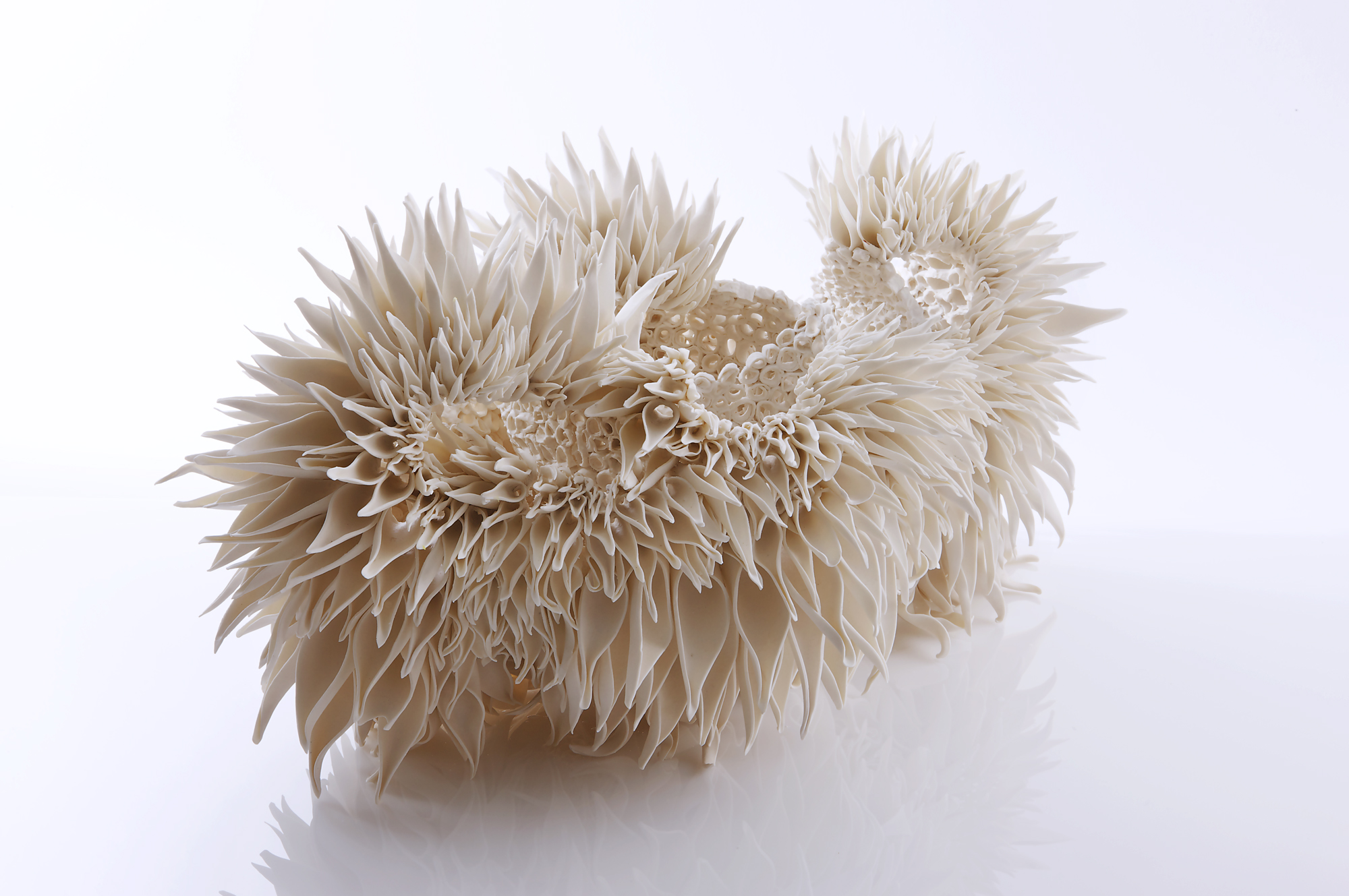 Intricate white sculpture resembling a cluster of teasel flowers, with sharp, textured petals and a glossy surface.