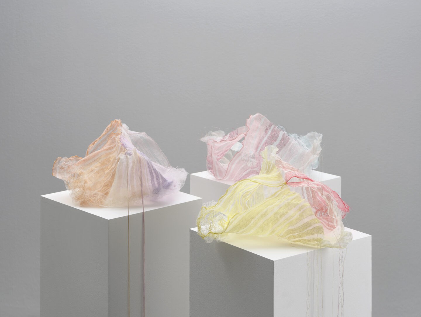 Three delicate, translucent sculptures in pastel colors displayed on white pedestals, part of Iben Høj's Mindcraft Projec...