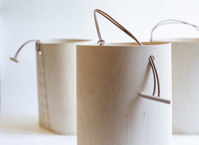 Eco-friendly wooden baskets with leather handles, displayed against a light background.