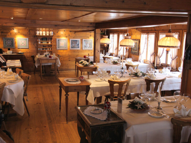 Cozy restaurant interior with wooden decor, neatly set tables, and warm lighting, suitable for a celebration.