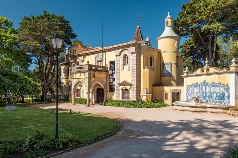Museum Condes de Castro Guimarães in Cascais, featuring yellow architecture and surrounding greenery under a clear blue sky.