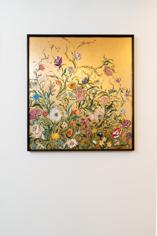 Vibrant floral artwork featuring various colorful flowers against a gold background, framed and displayed on a wall.