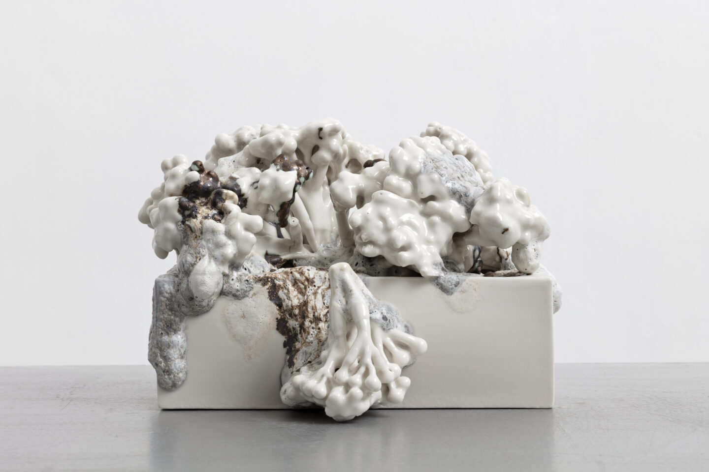 Abstract sculpture resembling crumbling nature, featuring organic forms in white and gray tones, reflecting themes of grow...