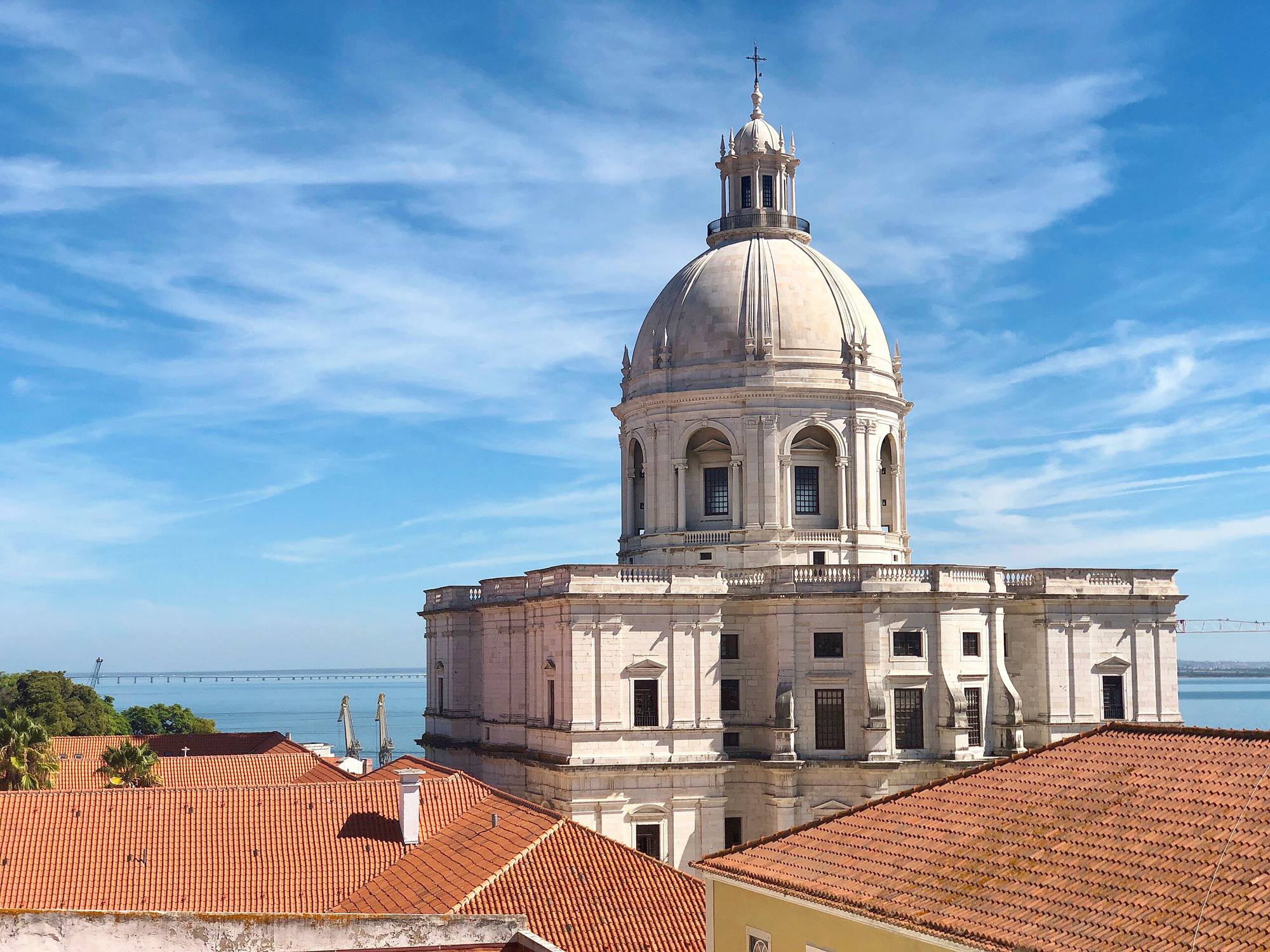 Church of Santa Engrácia with a prominent dome, surrounded by red-tiled roofs and a blue sky in the background.