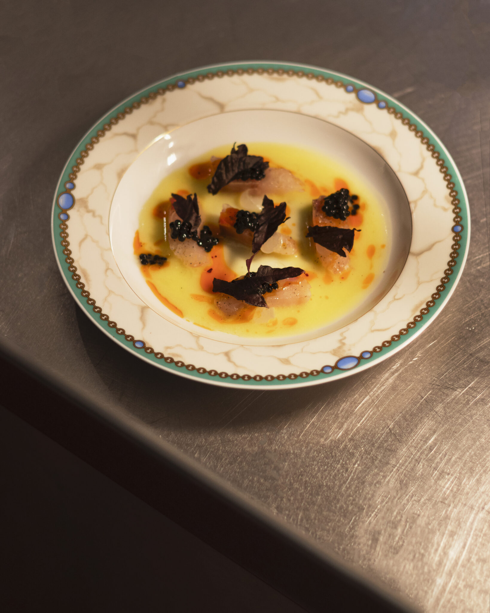 A beautifully presented dish in a decorative plate, featuring a creamy sauce, vegetables, and garnishes.