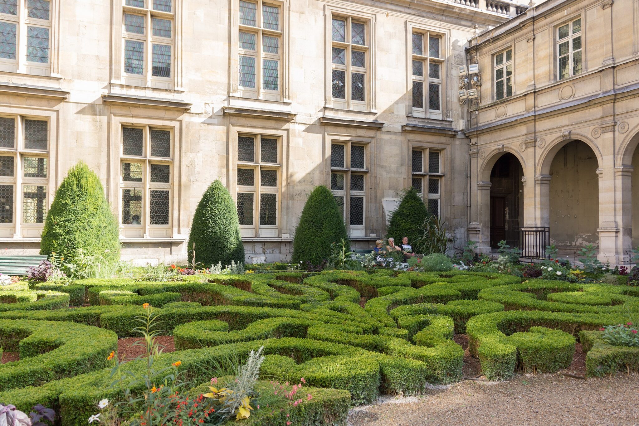 Lush, manicured hedges form a maze pattern in a quiet courtyard garden next to the Musée Carnavalet.