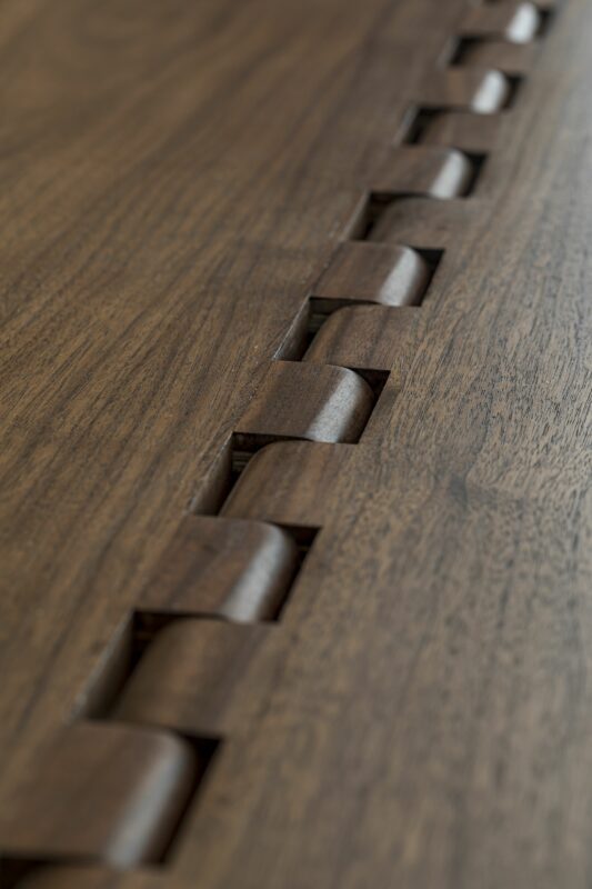 Wooden joinery featuring curved interlocking elements on a smooth wooden surface.