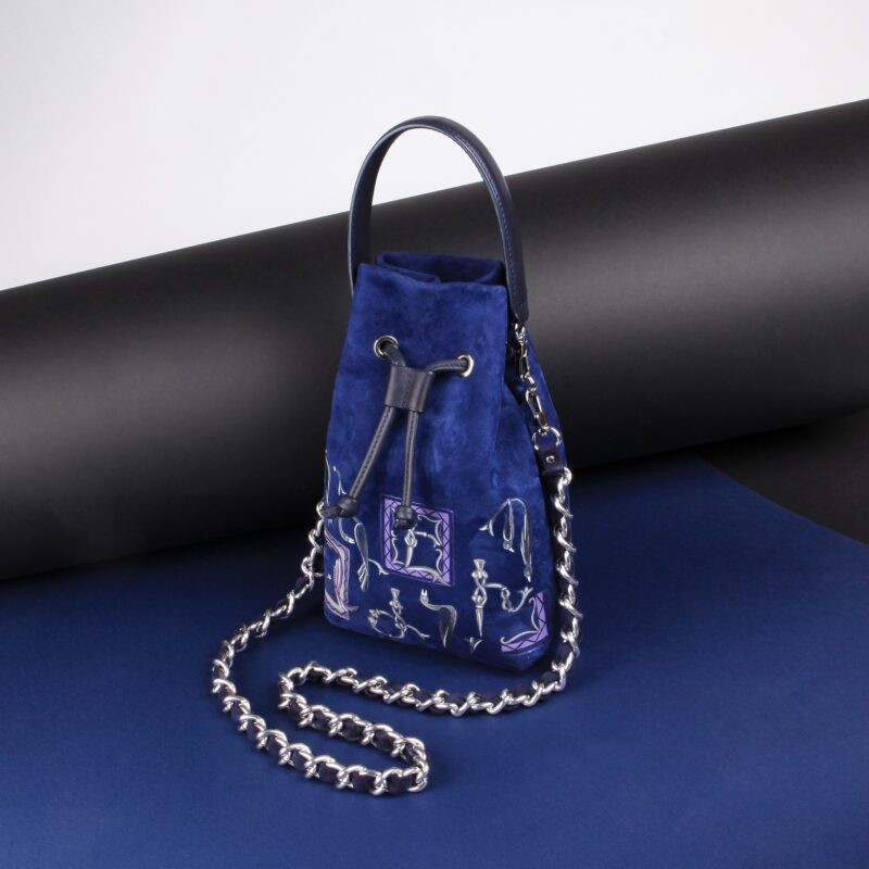 Royal blue suede MOLLY bag with a chain strap, featuring decorative elements, set against a dark background.