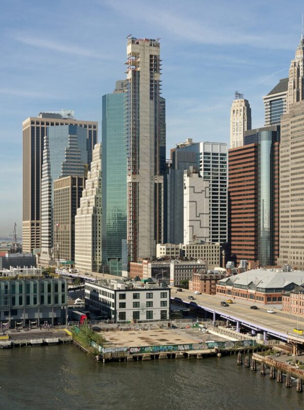 View of Manhattan skyline from Brooklyn Bridge, showcasing tall buildings and the East River.
