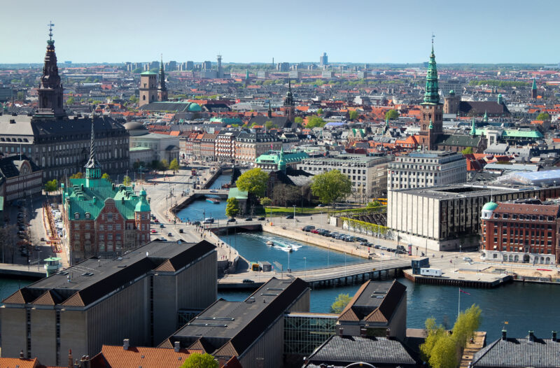 Aerial view of central Copenhagen showcasing narrow streets, crooked houses, and notable landmarks like Børsen and Christ...