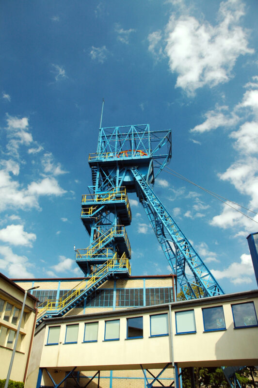 Blue mining tower with a staircase against a bright sky, part of the Guido Coal Mine in Zabrze.
