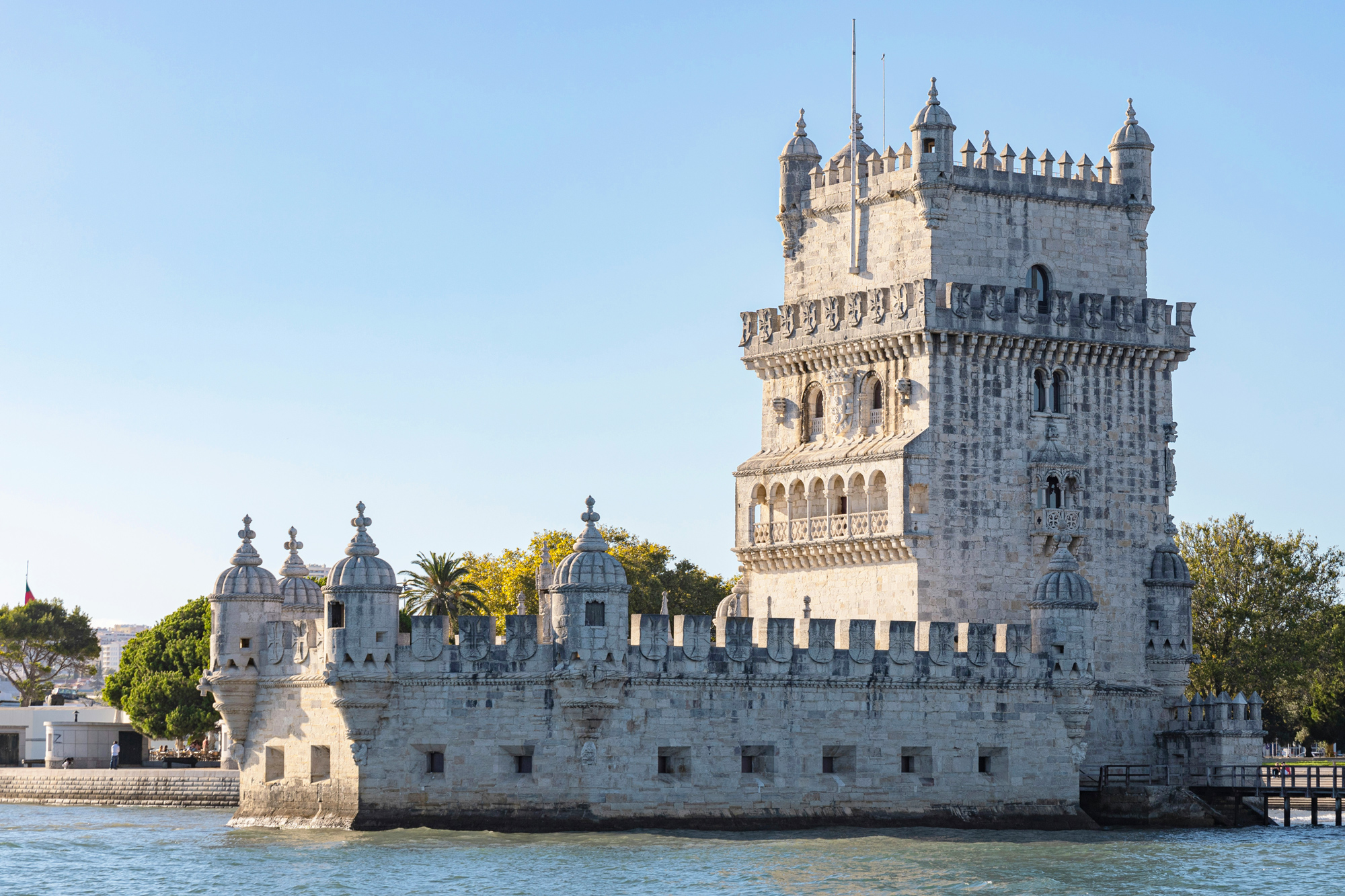 Belem Tower stands majestically by the water, showcasing its intricate stonework and historic architecture.