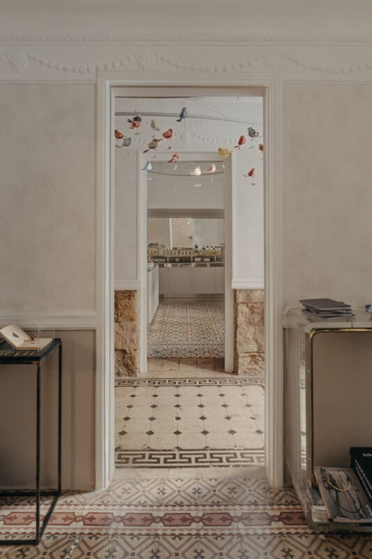 View through an archway into a stylish interior with patterned tile flooring and decorative ceiling elements.
