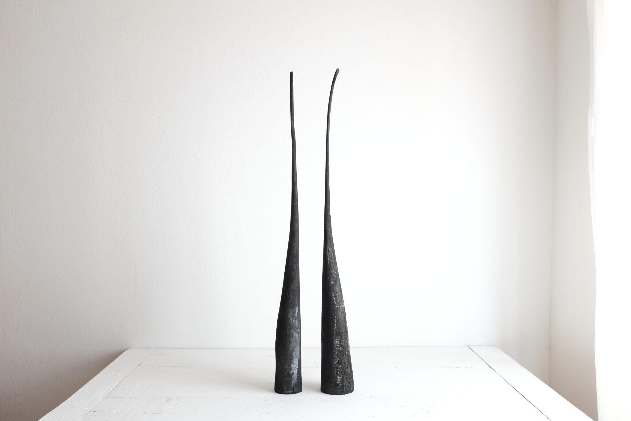 Sculpture titled "duo 2" by Marco Bellini, featuring two tall, slender, black forms against a light background.