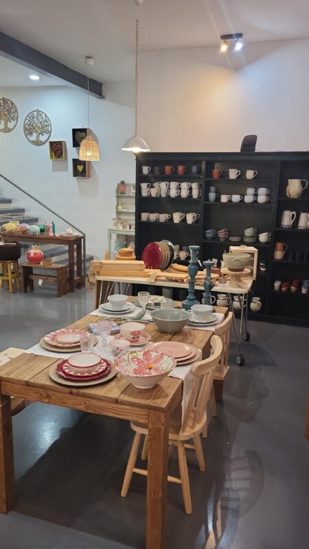 A cozy dining setup featuring wooden tables with various dishware, including plates and bowls, against a dark cabinet.