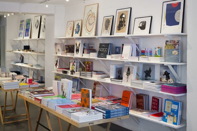 Colorful books and art prints displayed on shelves in the Cinnober bookstore, inviting for creative visitors.