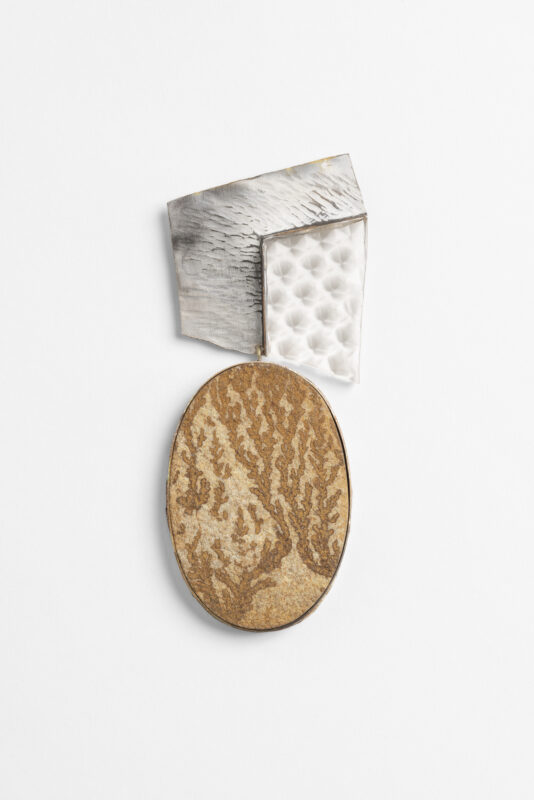 Abstract brooch featuring a textured oval in earthy tones, paired with metallic geometric shapes in silver and white.