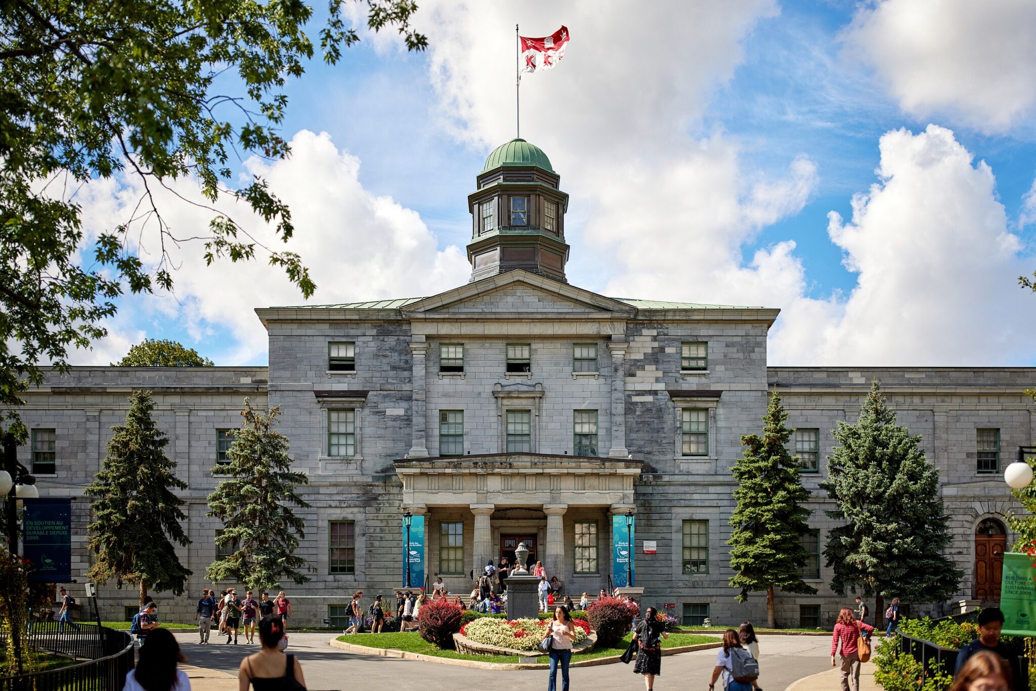 University of Montreal, where her dream became reality ©Arts Building at McGill University in Montreal, featuring a stone facade and Canadian flag, with people in front.