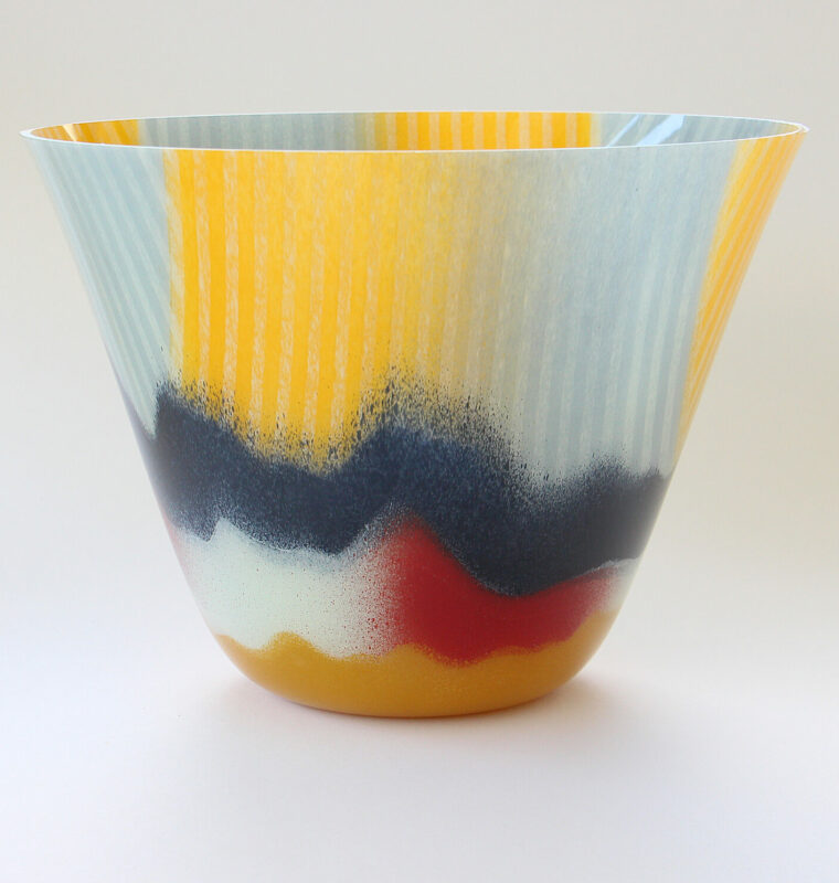 Colorful glass bowl with a textured surface featuring blue, yellow, and red hues, showcasing Camille Jacobs' artistry.