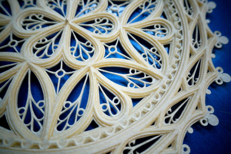 Intricate parchment rosette design inspired by a harpsichord by Girolamo Zenti, set against a blue background.