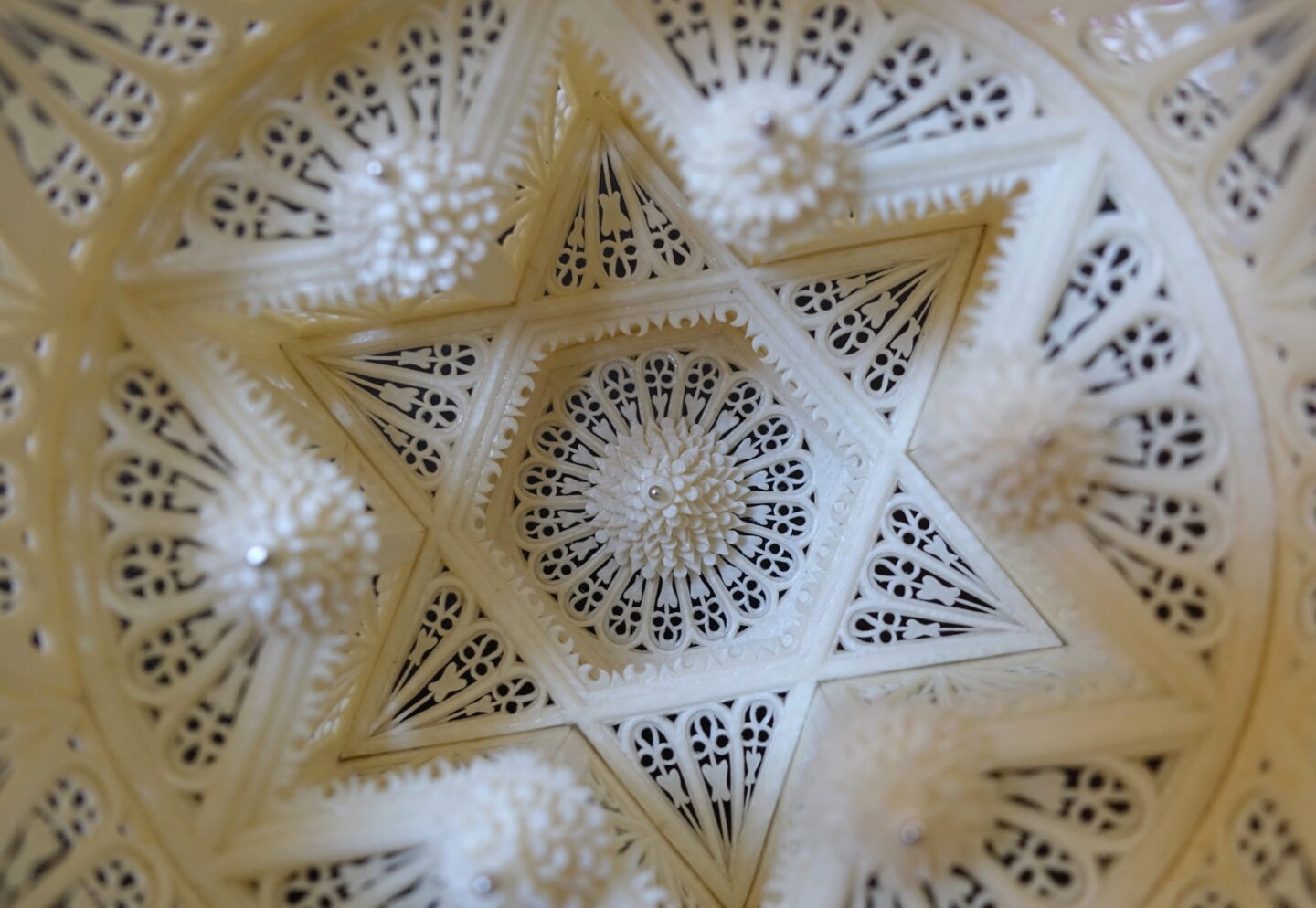 Intricate parchment rosette design, featuring a star shape and detailed carvings, inspired by a 1540 Venetian harpsichord.