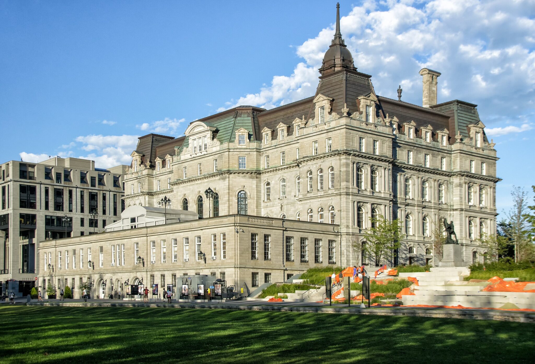Historic building in Montreal with ornate architecture, surrounded by green grass and orange accents in the foreground.