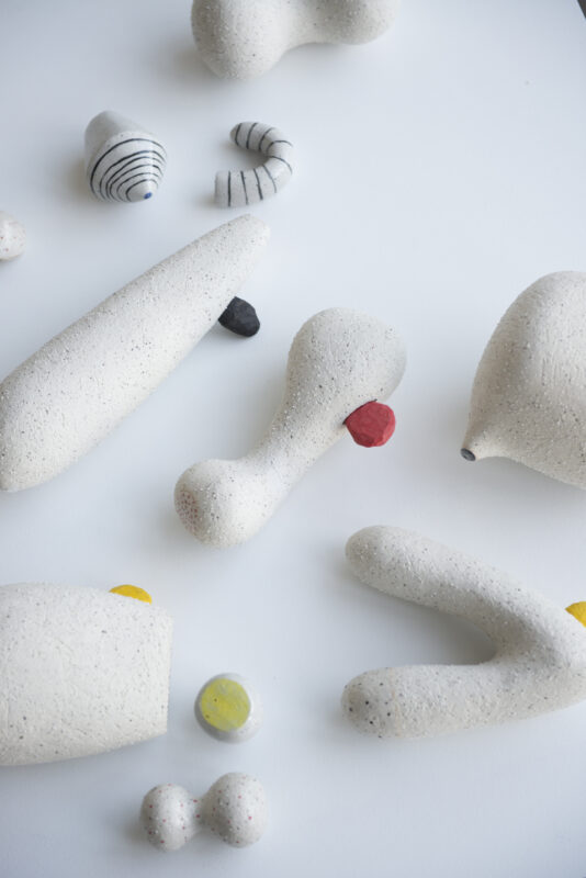 Abstract sculptures in various shapes and colors on a white surface, showcasing texture and motion.