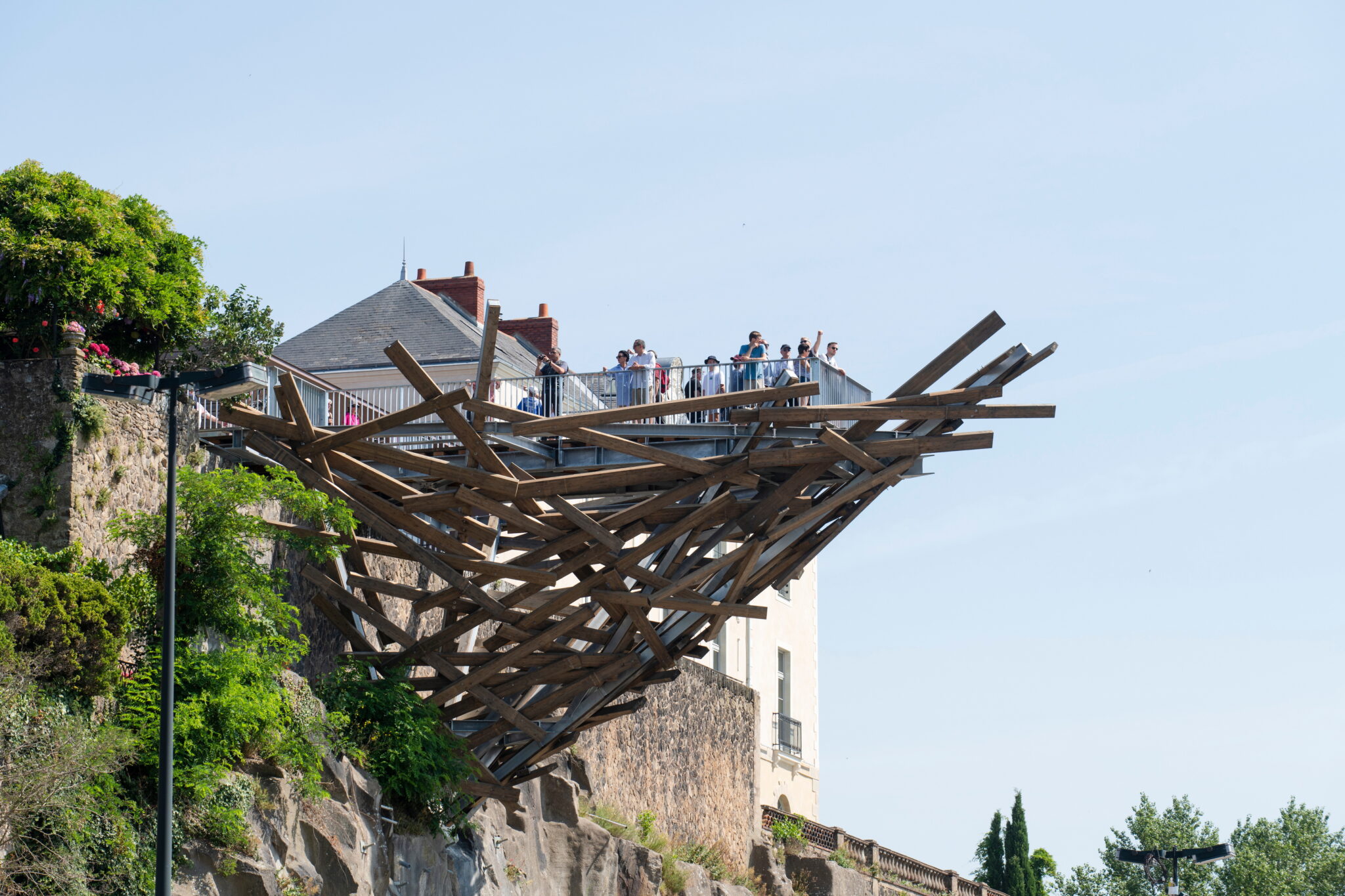 Wooden structure extending from a cliffside belvedere in Nantes, with visitors observing the view.