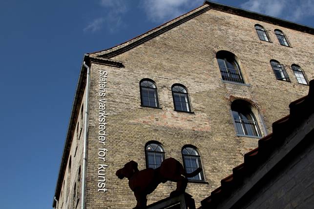 Historic building with large windows and a sculpture of a horse on the roof, labeled "Statens værksteder for kunst.