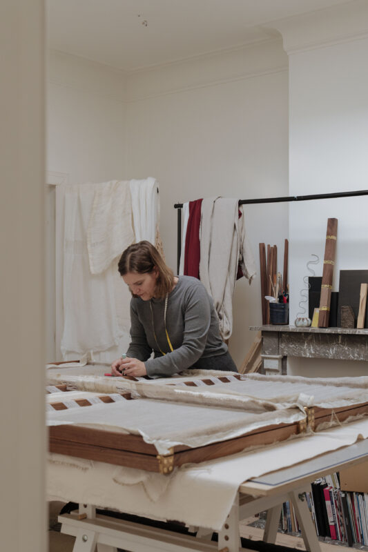 Van der Massen working in her studio, focused on a project with materials and tools around her.
