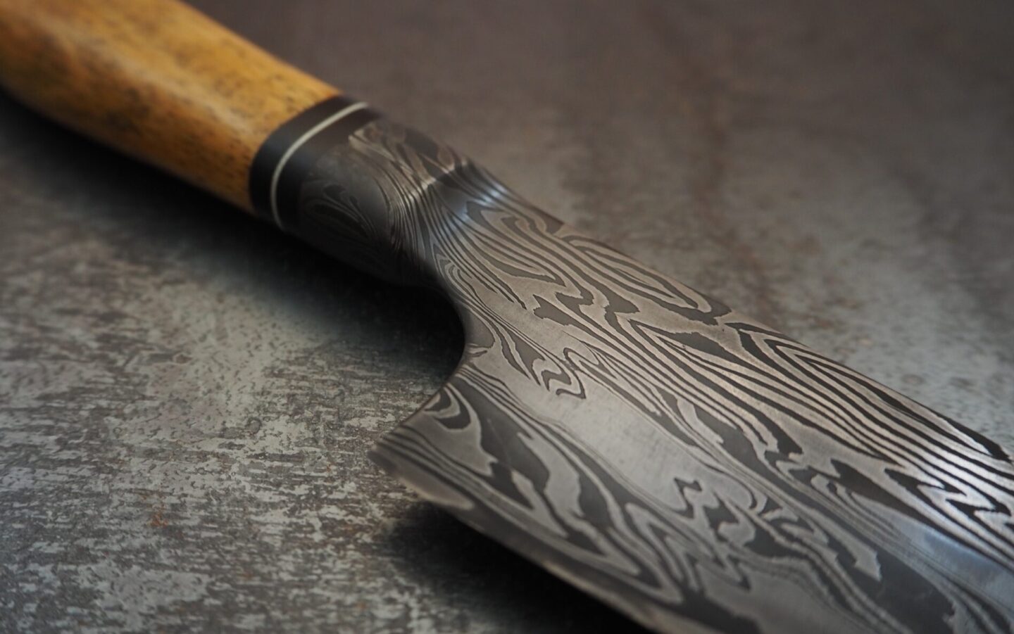 Detail of a marble-textured knife with a wooden handle, showcasing intricate patterns on the blade.