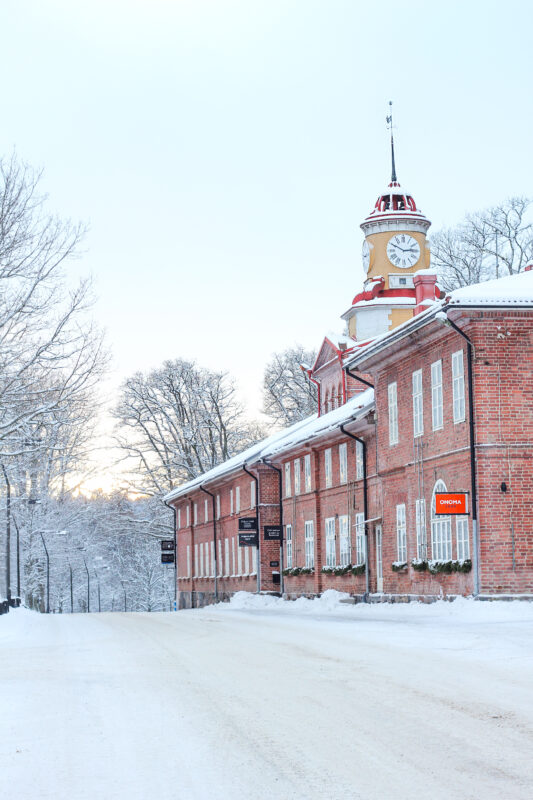 Cafe Antique's exterior in winter, featuring snow-covered ground and a clock tower against a pale sky.