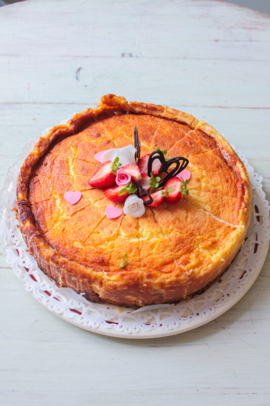 Cheesecake topped with strawberries and decorative elements on a white lace plate at Cafe Antique.