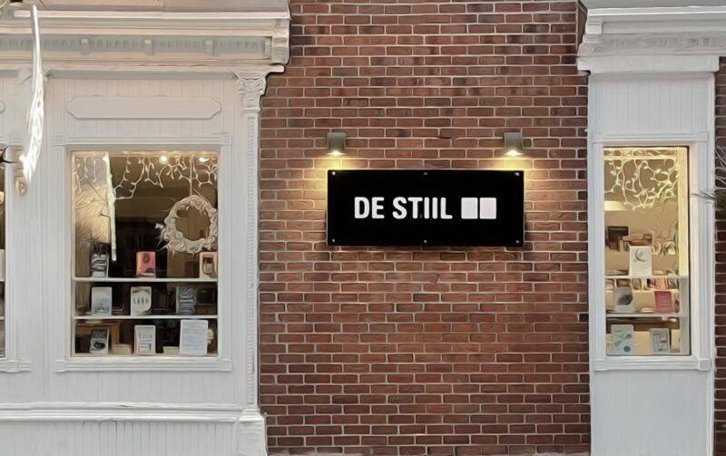 Exterior view of De Stiil, featuring a brick facade, large windows, and a modern sign.