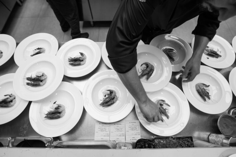 Carefully arranged plates with shrimp, as a chef garnishes dishes in the kitchen at Don Camillo.