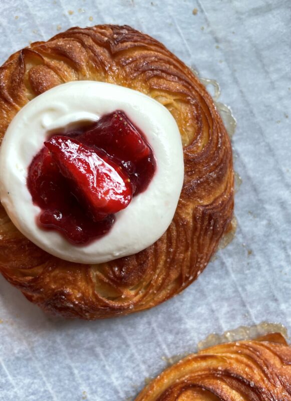 Golden pastry topped with cream and strawberry jam, showcasing a sweet treat from Juno the Bakery.
