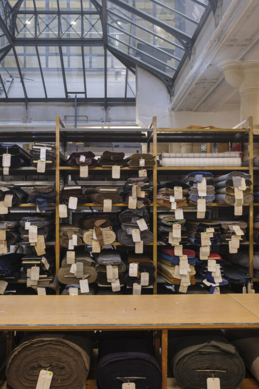 Shelves filled with various fabrics, each tagged, under a glass ceiling in Lafayette Saltiel Drapiers.