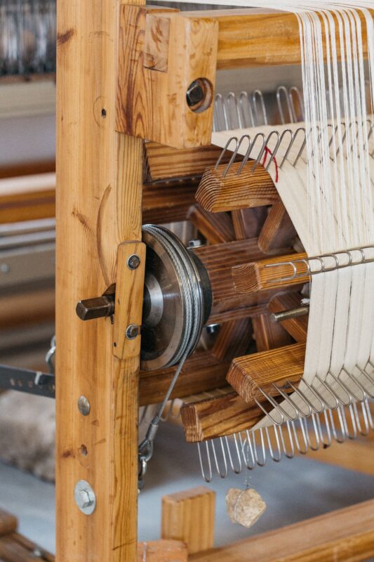 Wooden weaving loom with a metal pulley and threads, part of the ÁBBATTE project by Paco Marín.