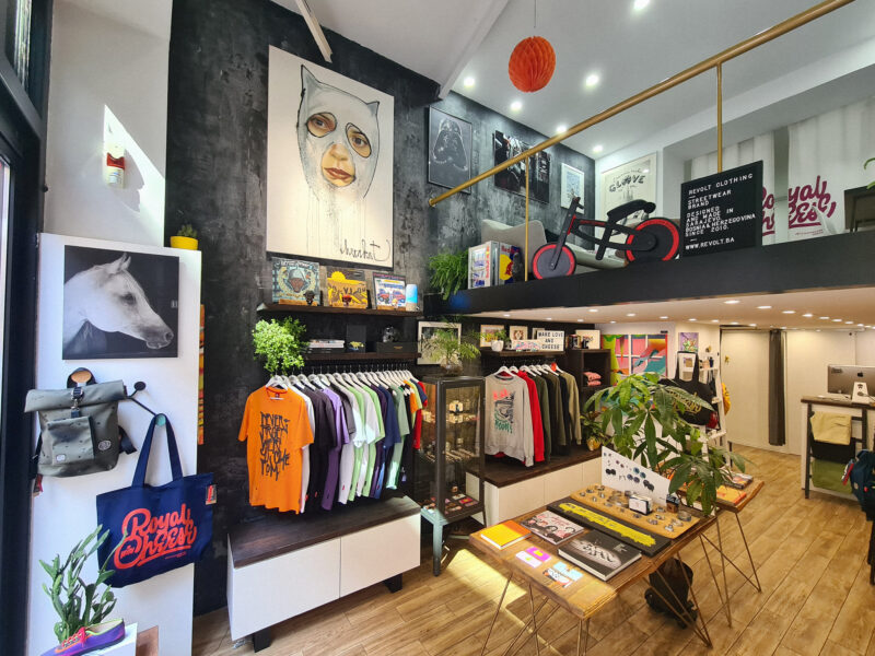 Interior of a clothing store featuring colorful apparel displays, artwork on walls, and a modern layout.