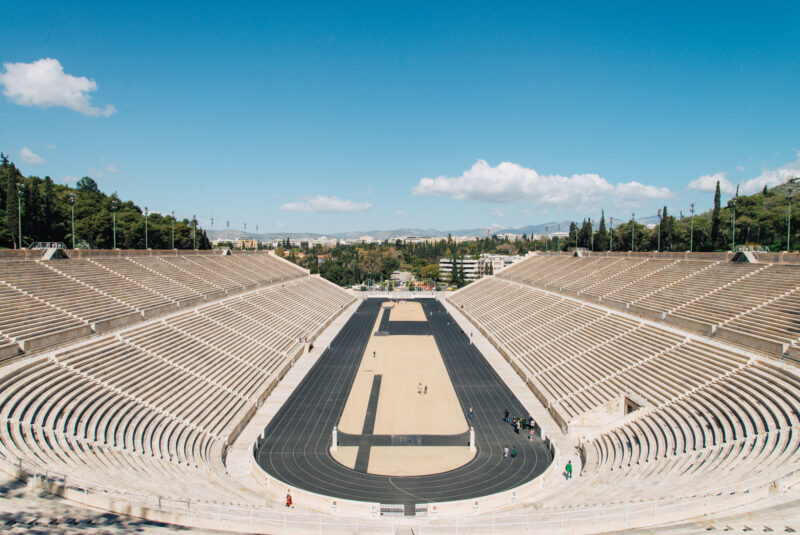 Panoramic view of the Panathenaic Stadium in Athens, showcasing its seating and track under a clear blue sky.