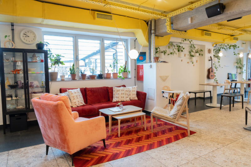 Cozy interior of Bistro Zdravo featuring colorful seating, plants, and a bright yellow ceiling.