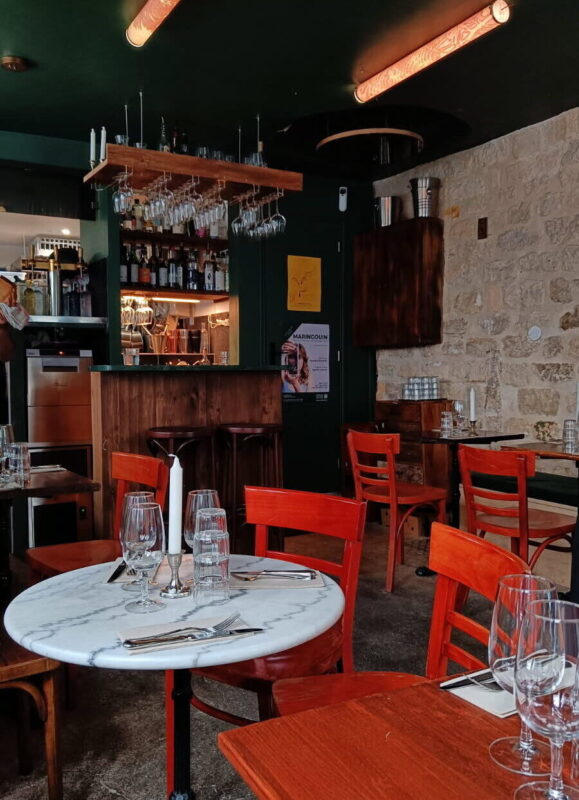 Red chairs around marble tables in a cozy restaurant with a bar in the background, showcasing playful energy.