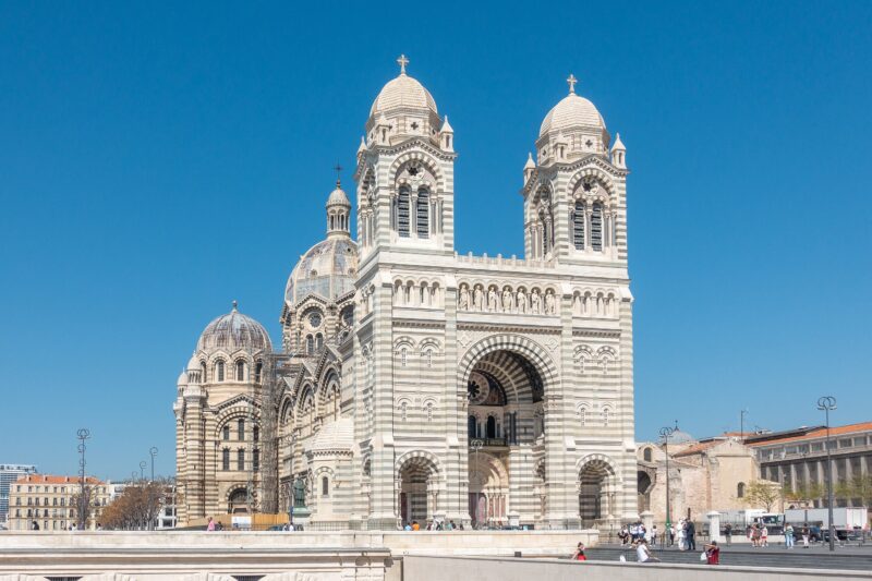 Byzantine-style Marseille Cathedral with twin towers and ornate facade against a clear blue sky.