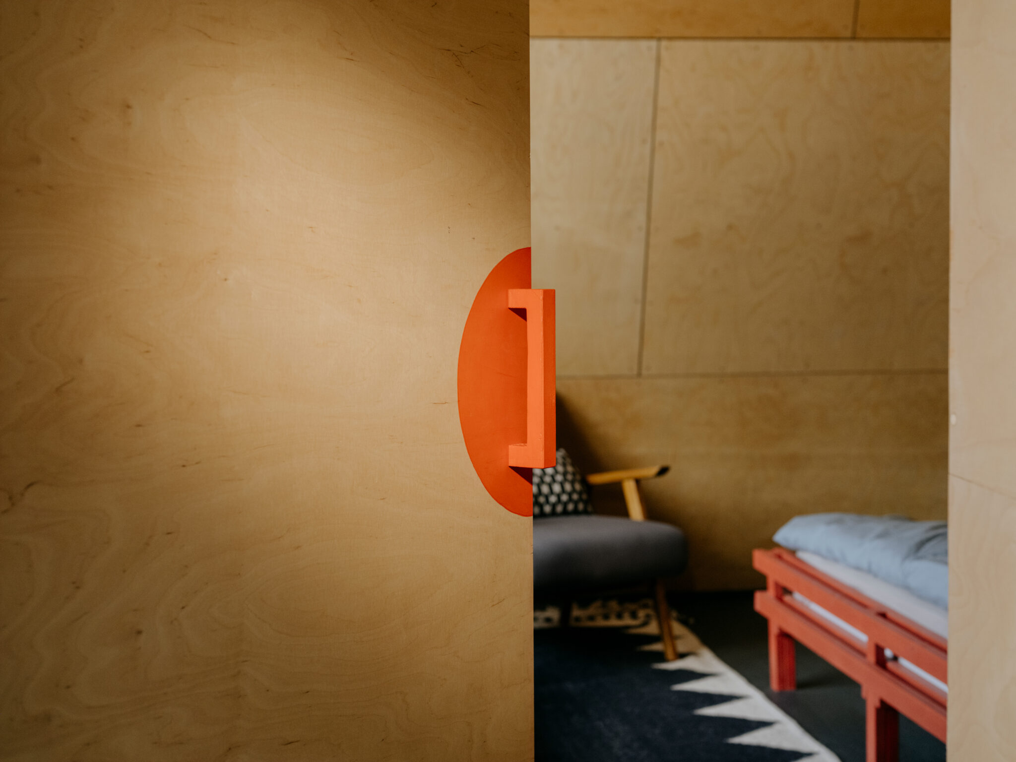 Interior view featuring a partially open door with an orange handle, revealing a cozy room with fiery accent colors in fur...