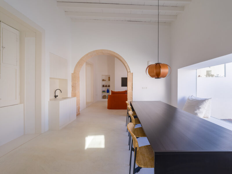 Bright, open interior featuring a dining table, archway, and a cozy living area with a red sofa.