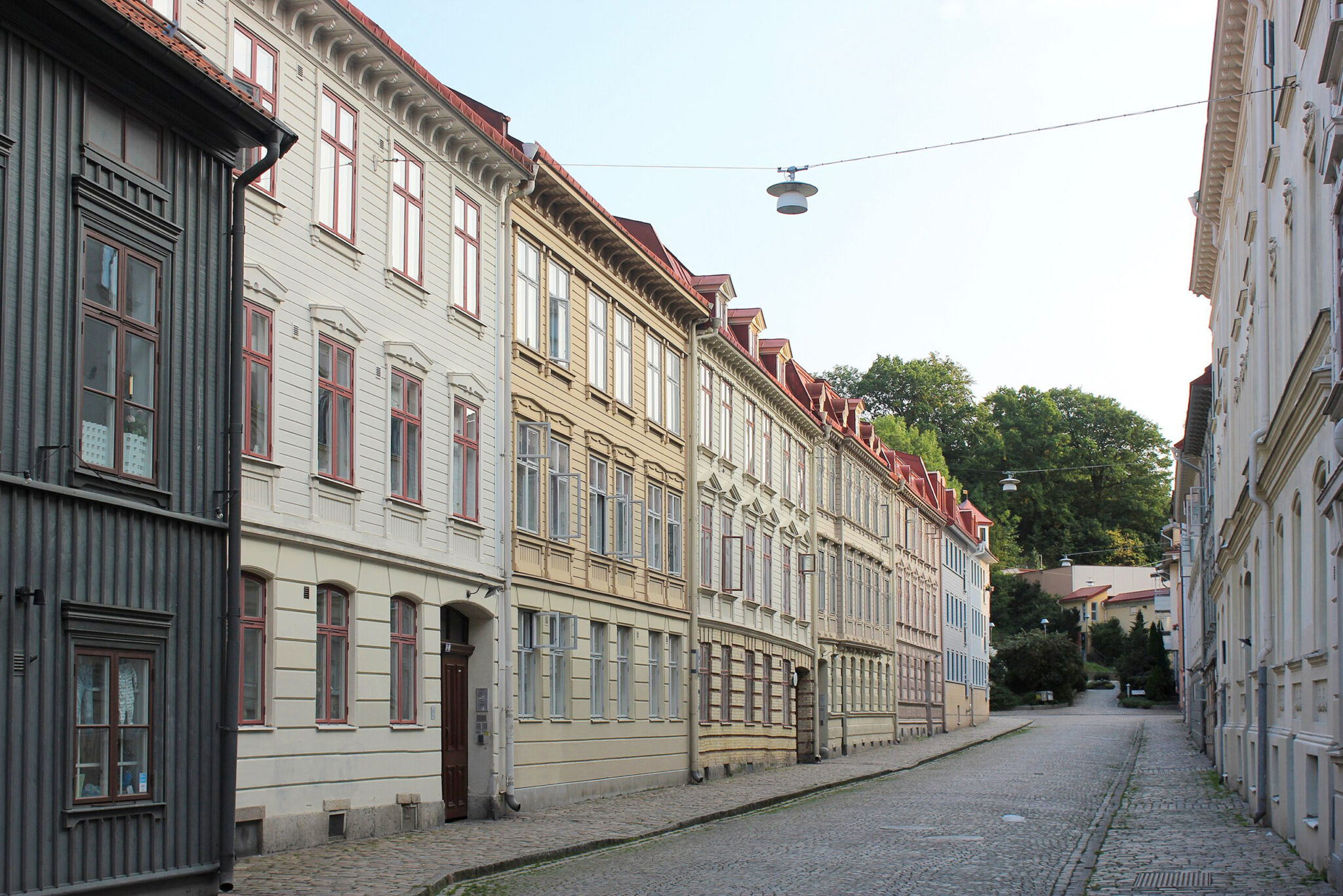 Quiet street in Gothenburg lined with old facades, featuring colorful buildings and cobblestone pavement.