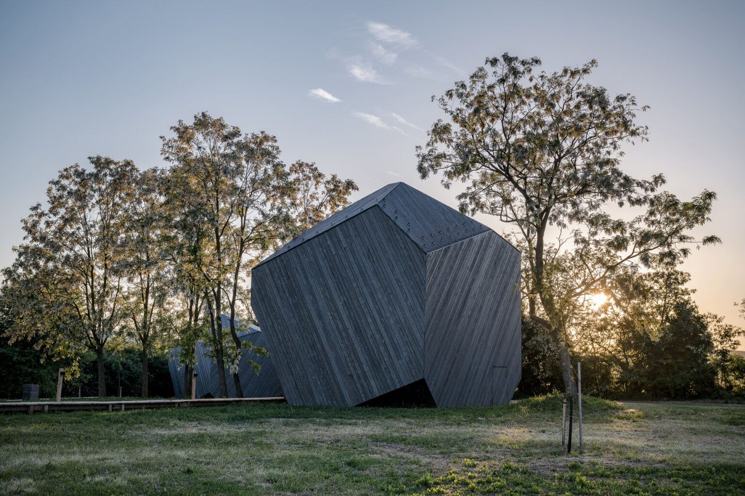 Modern wooden cabin with a unique angular design, surrounded by trees at sunset in Rock Cabins resort.