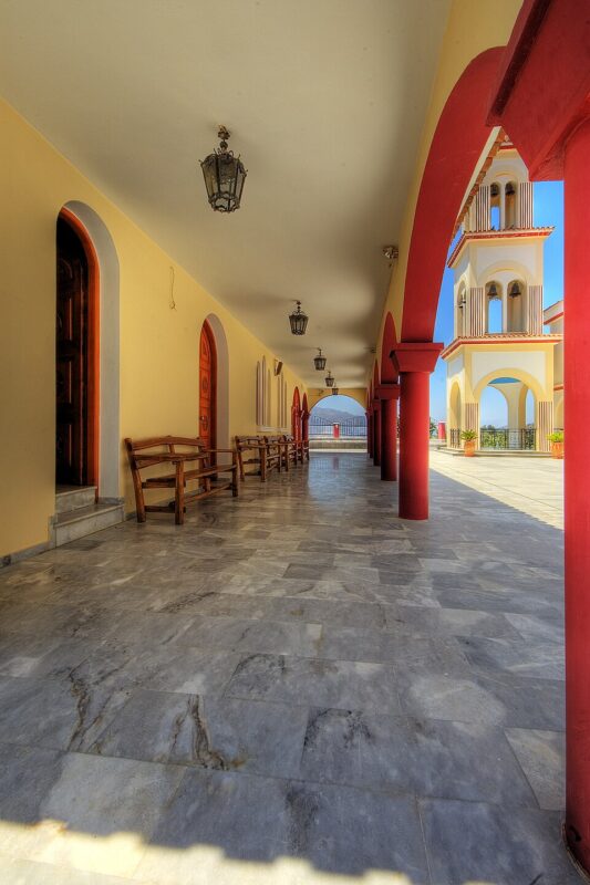 Colorful architecture in Spili, Crete, featuring arched doorways and a marble floor under a clear sky.